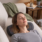 Femme détendue utilisant un coussin cervical chauffant RelaxCocoon gris sur un canapé confortable